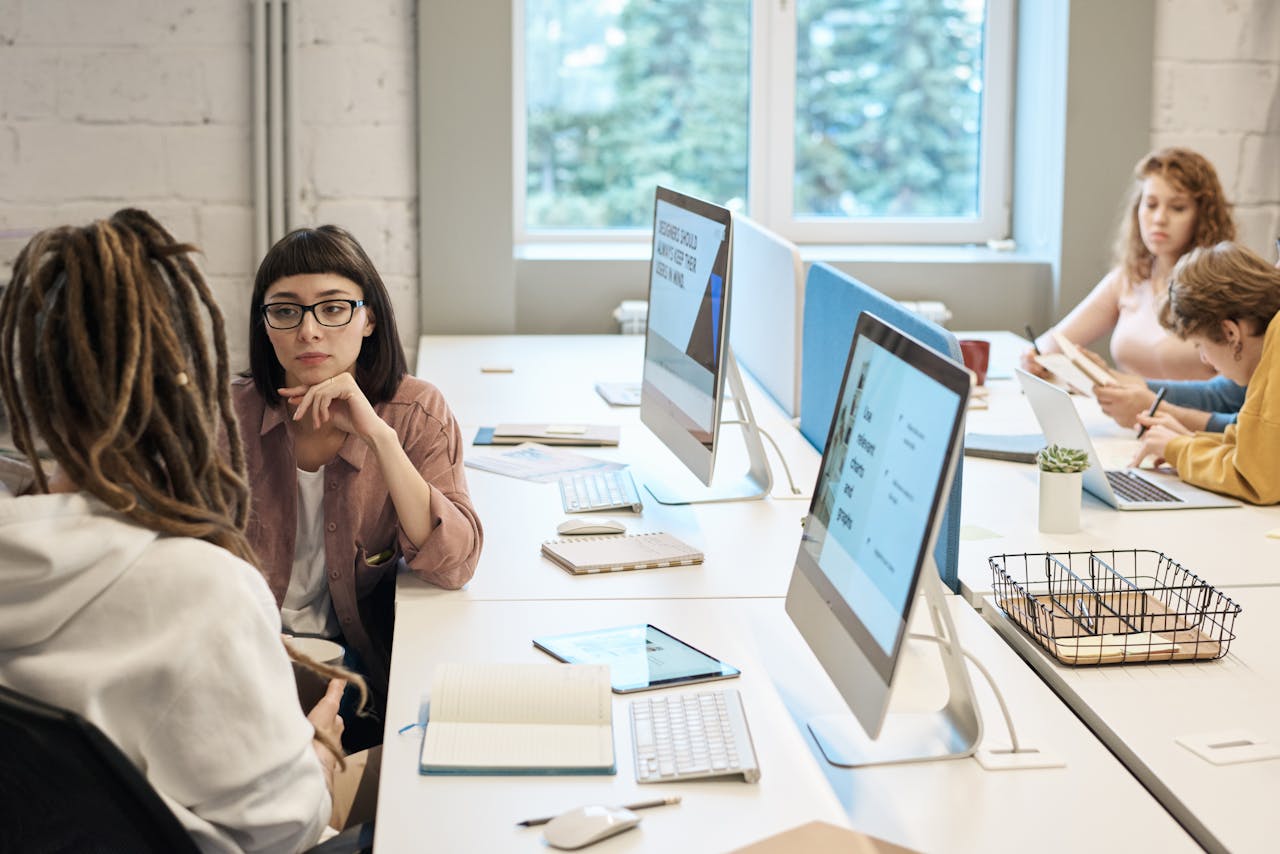 about-01 Diverse group of women working together in a modern office setting, fostering teamwork and creativity.