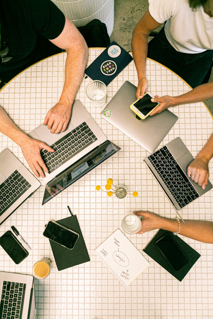 services-04 Top view of a team collaborating with laptops, phones, and notes in a modern office.