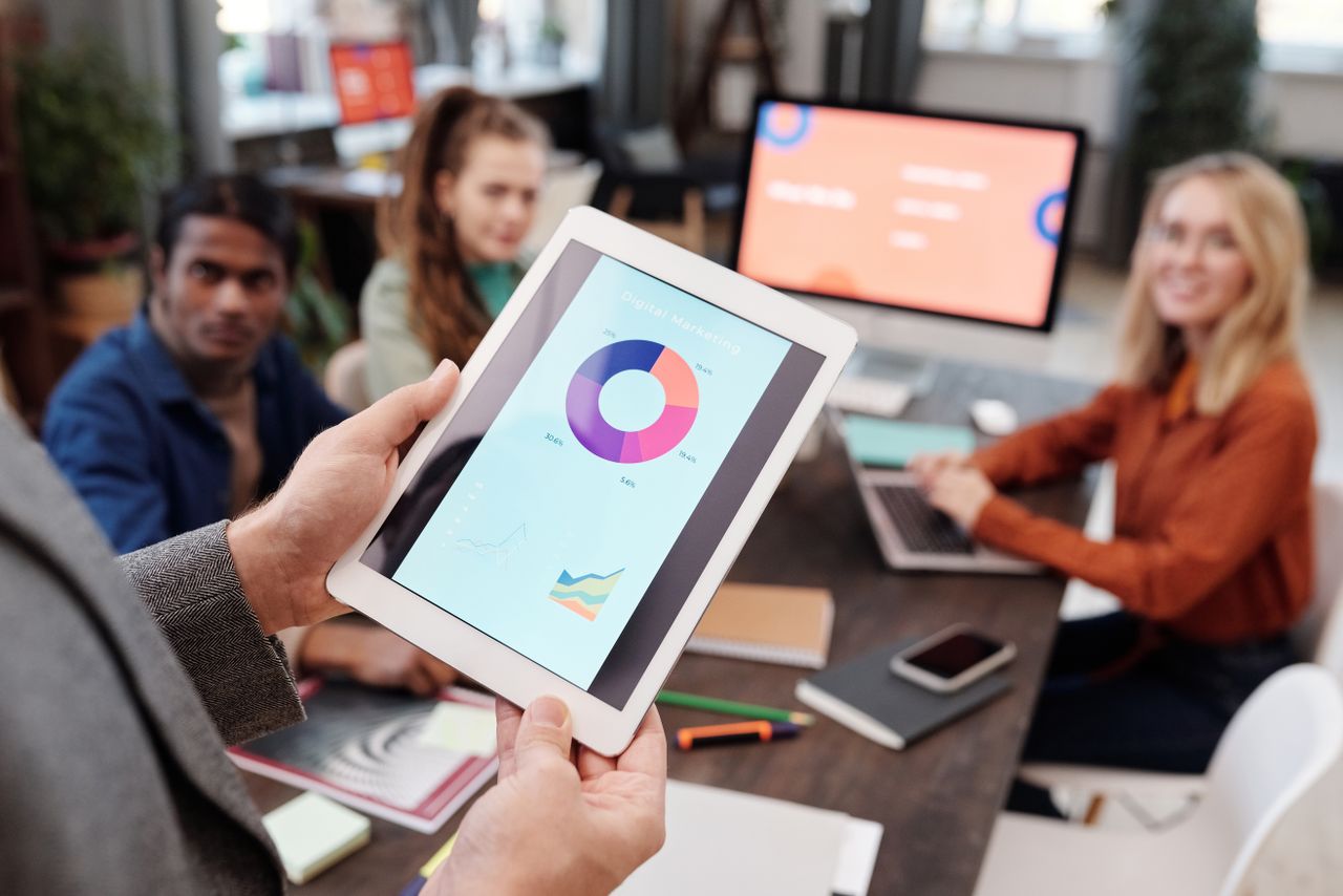 gallery-3 Business team using a tablet to analyze digital marketing data with charts in an office setting.