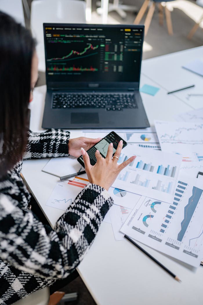 contact-img Businesswoman evaluating stock market trends using graphs and smartphone in office.